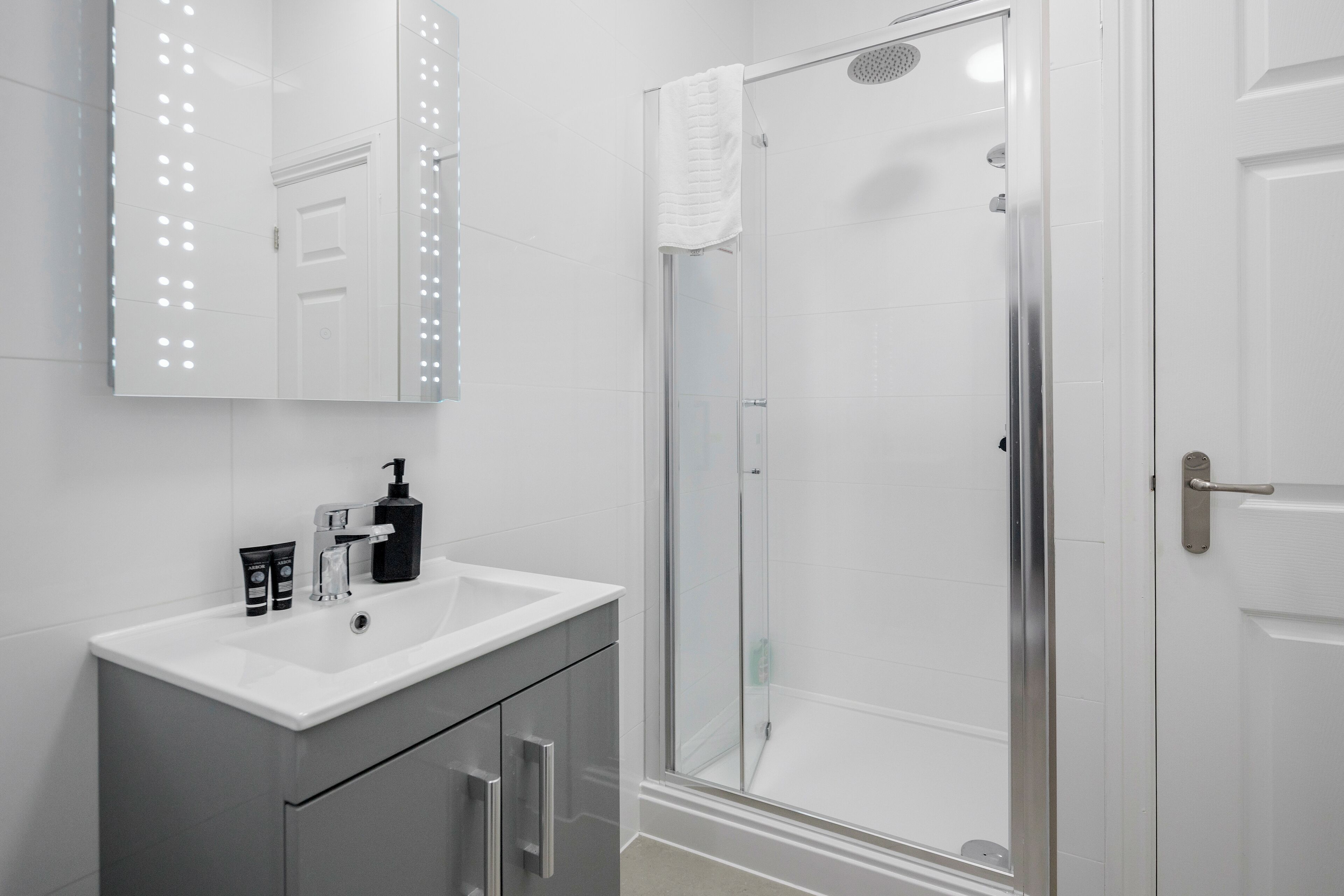 A bathroom with a white sink, mirror, and shower.