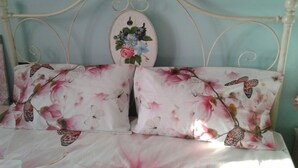 A bed with floral-patterned pillows and a decorative headboard. - Casa Annick Holiday Home (Barberino Tavarnelle)