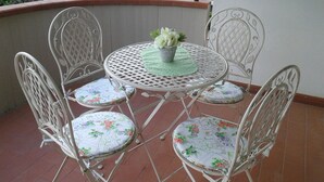 A round metal table with floral cushions and a potted plant, surrounded by metal chairs on a tiled patio. - Casa Annick Holiday Home (Barberino Tavarnelle)