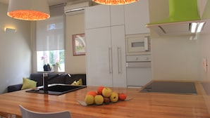 Uma cozinha moderna com armários brancos, micro-ondas e uma fruteira sobre o balcão.