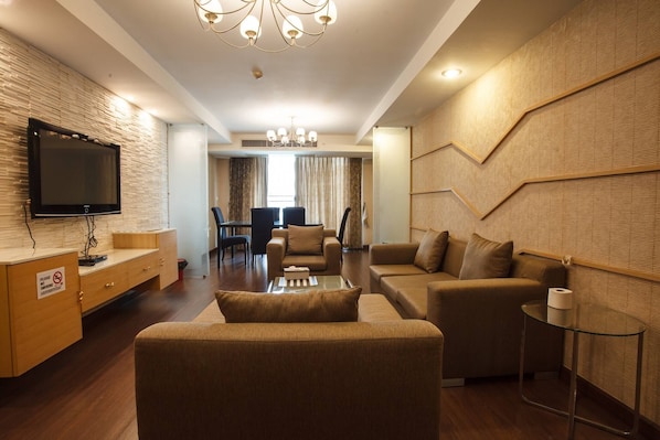 A modern living room with a flat-screen TV, a dining area, and a sofa set.