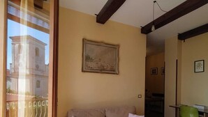Un salon avec un canapé beige, un tableau accroché au mur et une vue à travers une porte vitrée.