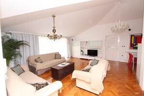 Relax in this spacious living area with a high ceiling, featuring a large coffee table, comfortable sofas, and a flat-screen TV.
