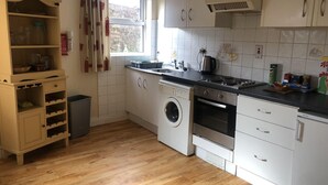 Een moderne keuken met witte kasten, een ingebouwde wasmachine, een fornuis en een koffiezetapparaat.