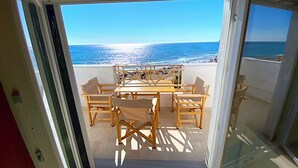 Un balcon avec une table et des chaises, donnant sur une plage.