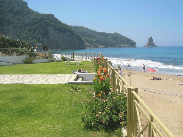 Un hotel costero con césped, piscina y vista al mar.