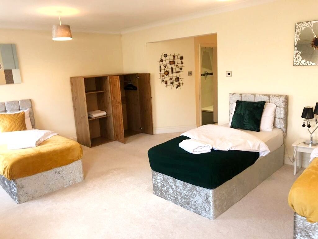 A bedroom with two beds, a wardrobe, a mirror, and a hanging light fixture.