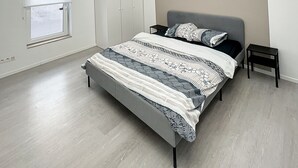 A modern bedroom with a skylight, a bed with patterned bedding, a bedside table, and a wardrobe.