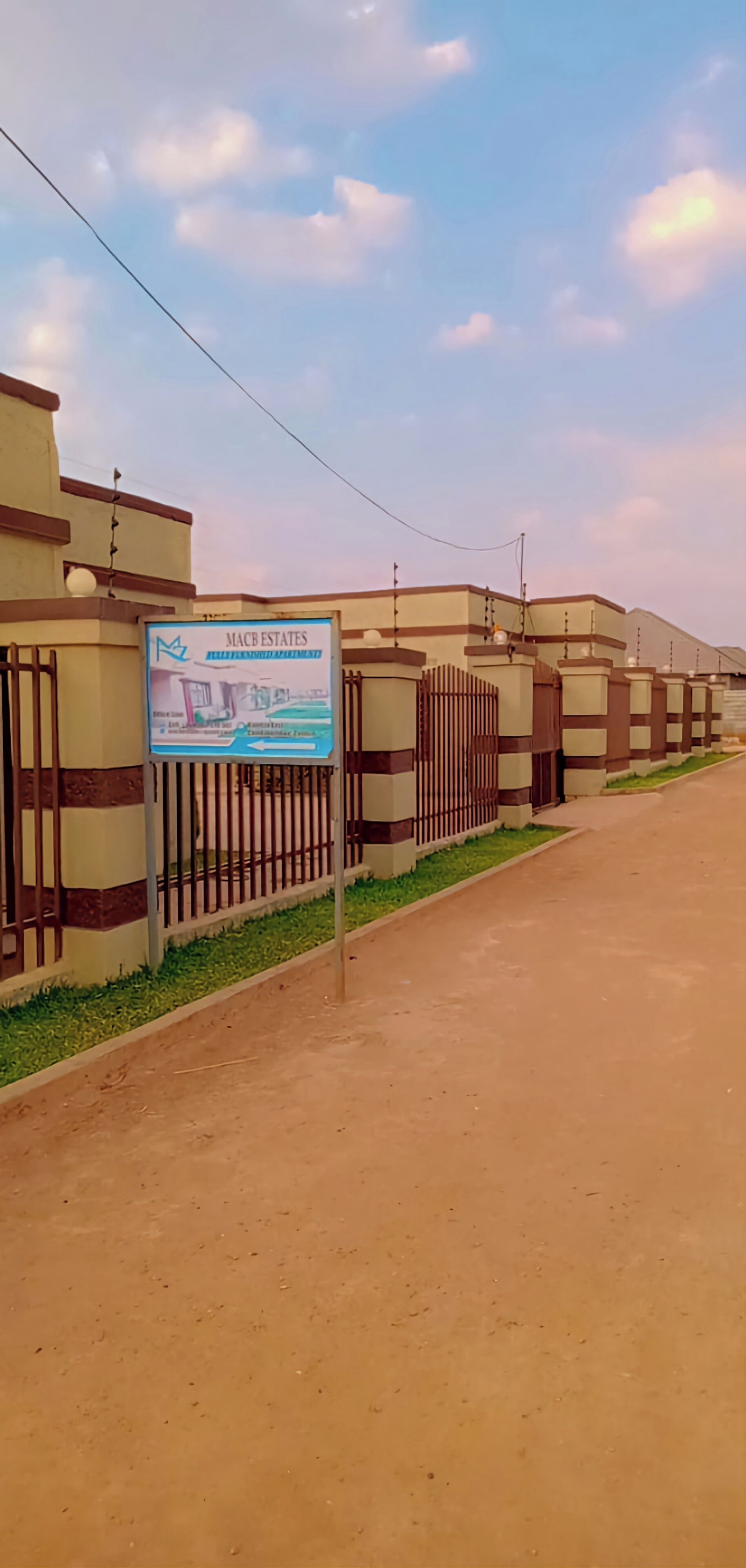 A gated residential area with a signboard for Mac Estates.