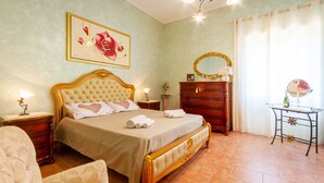 A bedroom with a large bed, a dresser, a vanity with a mirror, and a floral painting on the wall. - Relax in Style in Porto Cesareo's Hidden Gem (Porto Cesareo)