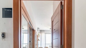 A hallway with wooden doors, a sign with 'S 1404', and a view into a dining area with chairs and a table. - Apartamento S1404 - Downtown Santo Domingo (Santo Domingo)
