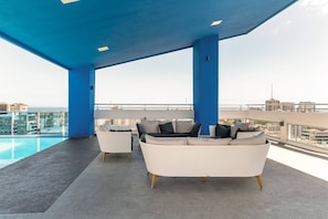A rooftop lounge with a pool, white wicker furniture, and a view of the city skyline. - Apartamento S1404 - Downtown Santo Domingo (Santo Domingo)