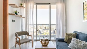 A modern living room with a sofa, a chair, a coffee table, and a balcony with a view of buildings. - Apartamento S1404 - Downtown Santo Domingo (Santo Domingo)