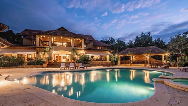 Una casa grande de dos pisos con piscina y zona de estar al aire libre.