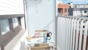 Un balcone con un tavolo apparecchiato per un pasto, una sedia e una pianta pensile.