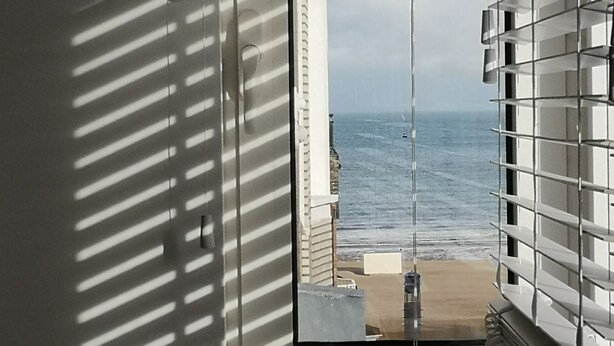 Una stanza con vista sul mare, incorniciata da persiane.