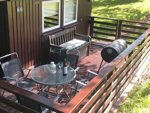 A deck with a glass table, chairs, a barbecue grill, and a wooden bench. - Nuthatch Lodge is set in 24 Acres of Wood, Parkland Near the Village of Cenarth (Newcastle Emlyn)