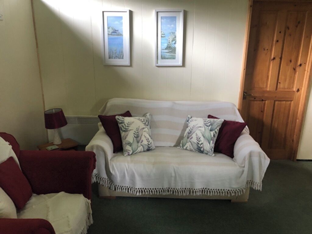 A room with a sofa, two pillows, a lamp, and a door.