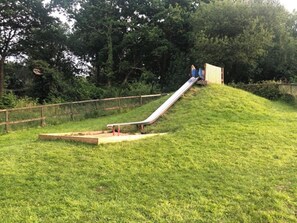 A playground with a slide and a small wooden structure. - Nuthatch Lodge is set in 24 Acres of Wood, Parkland Near the Village of Cenarth (Newcastle Emlyn)
