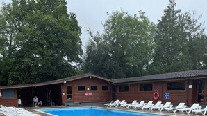 A swimming pool area with lounge chairs, a wooden building with a 'DEEP END' sign, and a lifebuoy. - Nuthatch Lodge is set in 24 Acres of Wood, Parkland Near the Village of Cenarth (Newcastle Emlyn)
