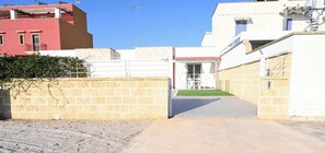 A narrow alleyway with a stone wall on one side and a building entrance on the other.