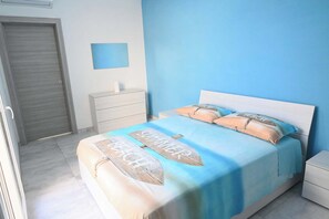 Une chambre à coucher comprenant un lit, une table de chevet, une commode et une porte.