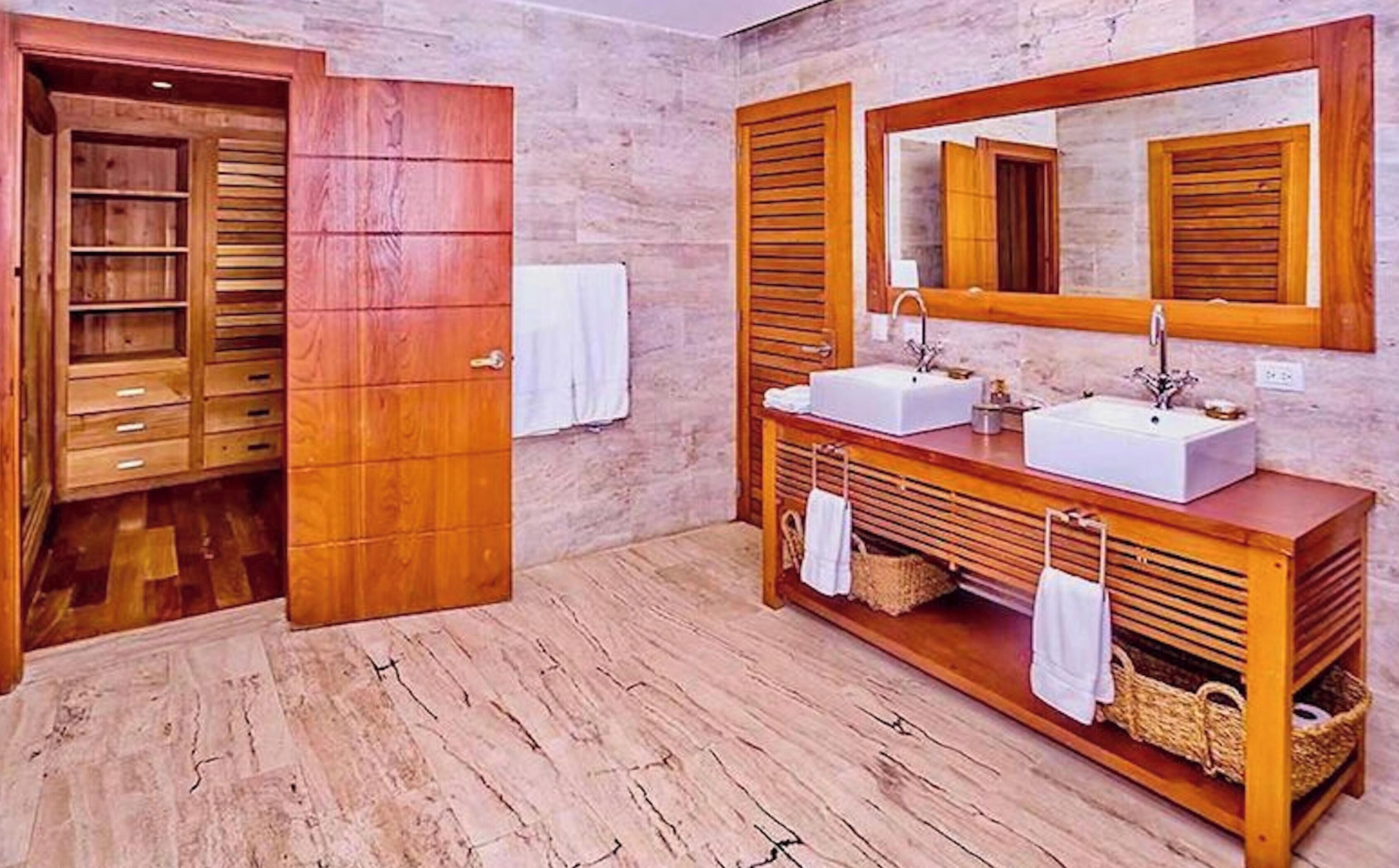 Ein Badezimmer mit Holzschränken, zwei Waschbecken und einem großen Spiegel.