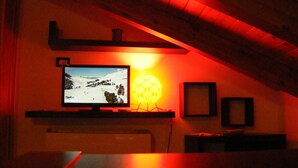 A room with a television mounted on a wall, a lamp, and a framed picture. - Villetta Singola a 20metri dal Mare per Soggiorni - Cure Termali Vicino Taormina (Ali Terme)