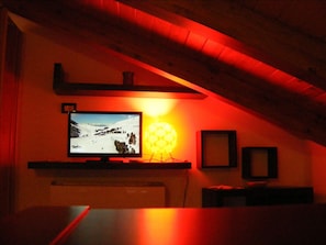 A room with a television mounted on a wall, a lamp, and a framed picture.
