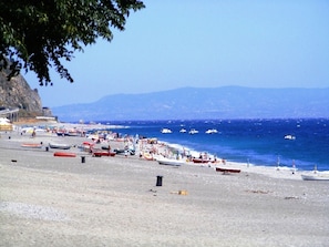A beach with boats and people.