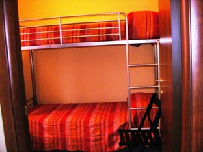 A bunk bed with a striped blanket and a pillow.