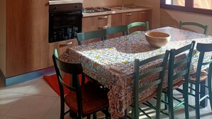 A kitchen with wooden cabinets, a microwave, stove, and a dining table with chairs.