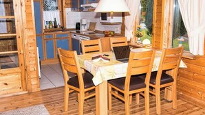 A wooden cabin with a dining area, kitchen, and a view of the garden. - This is Your House to Stay for Holidays (Oberharz am Brocken)