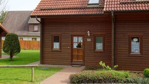 A wooden house with a tiled roof, a number '59' on the front, and a small window with a light fixture above the door. - This is Your House to Stay for Holidays (Oberharz am Brocken)