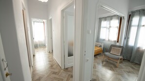 A room with a herringbone-patterned floor, a bed with a wooden headboard, and a chair with a cushion. - Lovely 1-bedroom Flat In Skopelos (Skopelos)