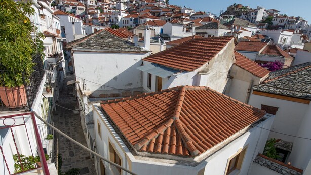 A narrow street with terracotta-tiled buildings, a red railing, and a clear blue sky. - Lovely 1-bedroom Flat In Skopelos (Skopelos)