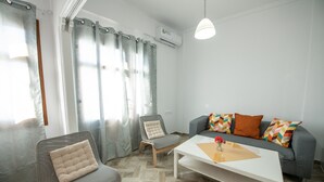 A modern living room with a grey sofa, a grey armchair, a white coffee table, and a small side table with a vase. - Lovely 1-bedroom Flat In Skopelos (Skopelos)