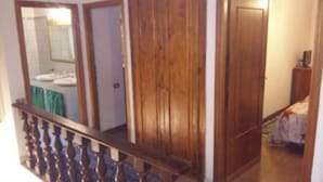 Una escalera con barandilla de madera que lleva a un cuarto con un armario de madera y una puerta.