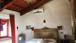 Un dormitorio con techo de madera, una araña, una cama, aire acondicionado y una ventana con cortinas.