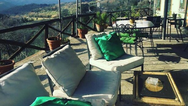 Una terraza con mobiliario exterior, plantas en macetas y vistas a montañas.