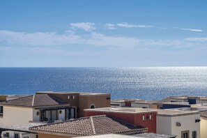 A coastal residential area with buildings featuring flat roofs and a clear view of the sea.