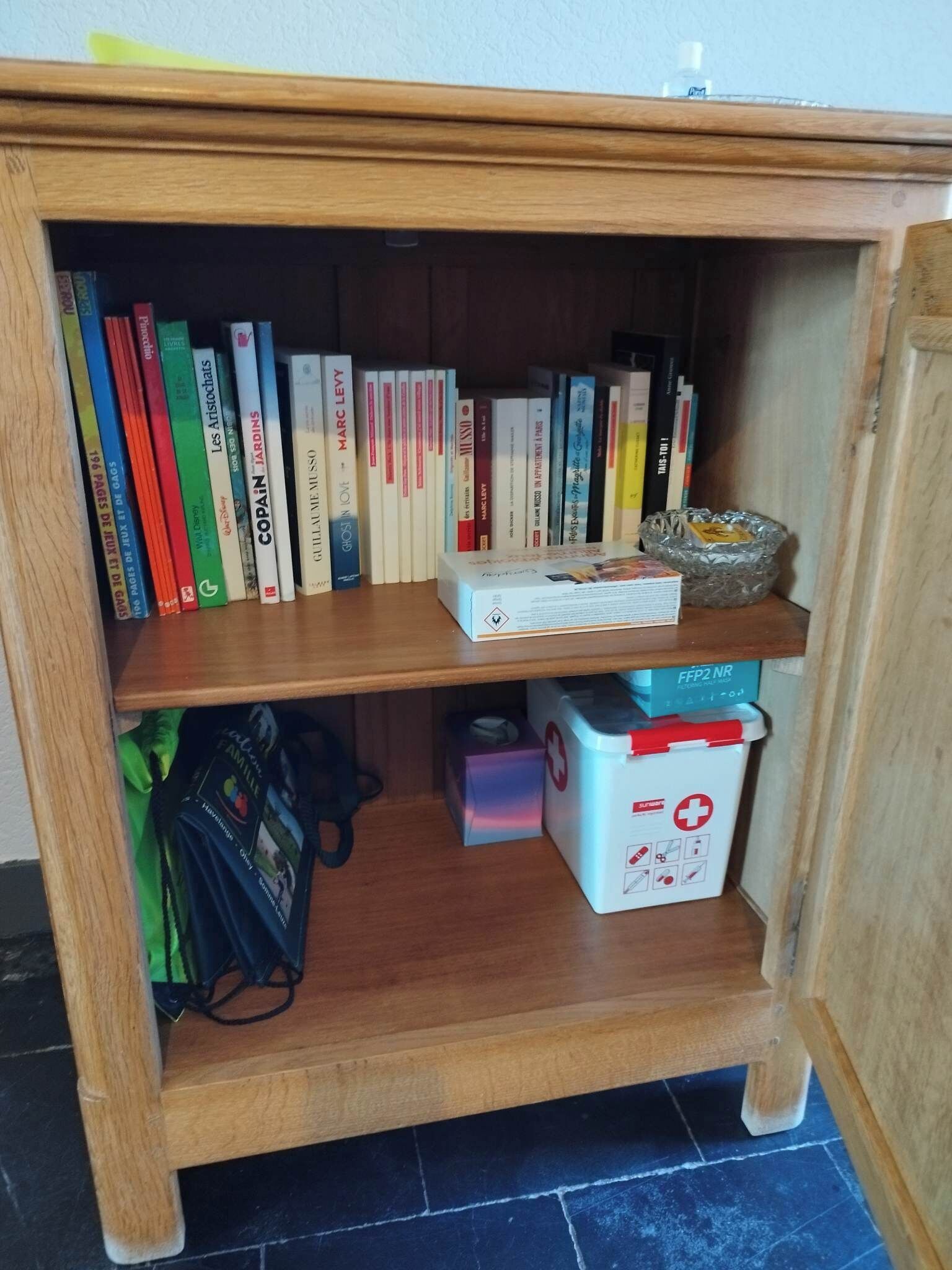 Une bibliothèque en bois avec des livres et une trousse de premiers secours.