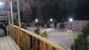 Una terraza de madera con vistas a zona boscosa y una zona con pozo de fuego.