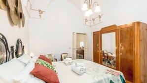 A hotel room with a bed, a wardrobe, a mirror, and a chandelier.