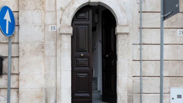 A stone building with a dark wooden door and an arrow sign pointing upwards.