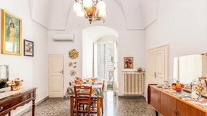 A dining area with a marble floor, wooden chairs, a table set for four, and a chandelier.