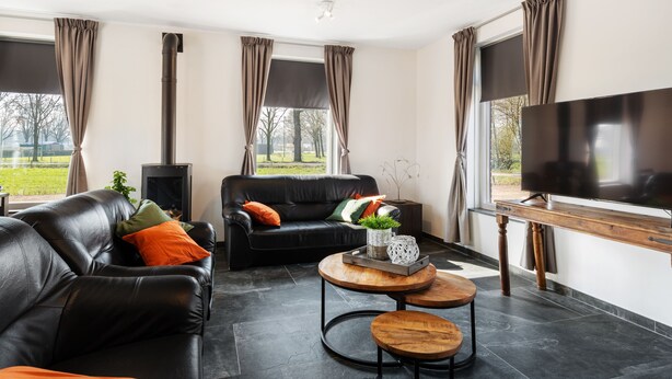 A modern living room with a black leather sofa, a wooden coffee table, and a flat-screen TV. - "cozy Luxury Holiday Home With Jacuzzi!" (Heumen)