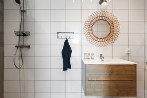 A bathroom with a shower, a sink with a wooden vanity, a towel rack, and a decorative mirror. - "cozy Luxury Holiday Home With Jacuzzi!" (Heumen)