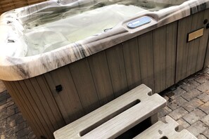 A hot tub with a marble exterior and a wooden panel design. - "cozy Luxury Holiday Home With Jacuzzi!" (Heumen)