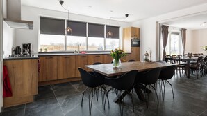 A modern kitchen with wooden cabinets, a large dining table, and black chairs. - "cozy Luxury Holiday Home With Jacuzzi!" (Heumen)